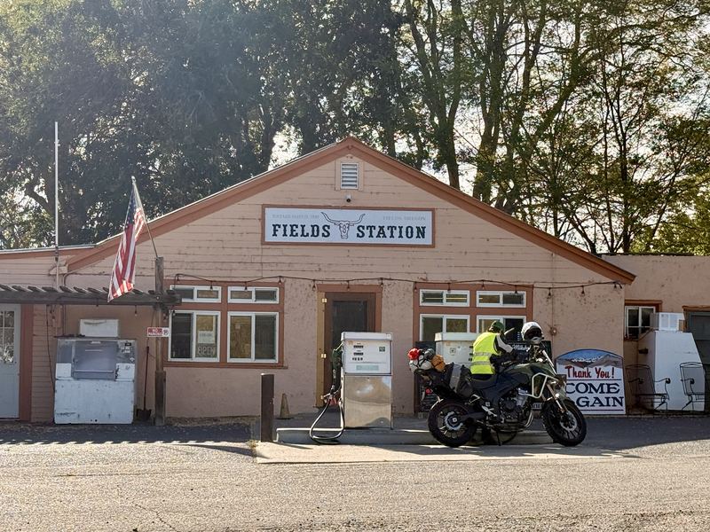 A rider fueling a green adventure bike at Fields Station