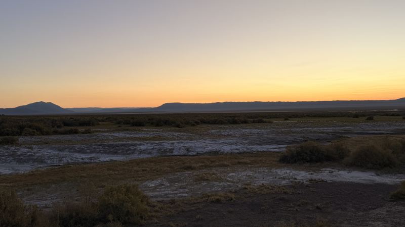 Sunset over the salt flats with mountains on the horizon