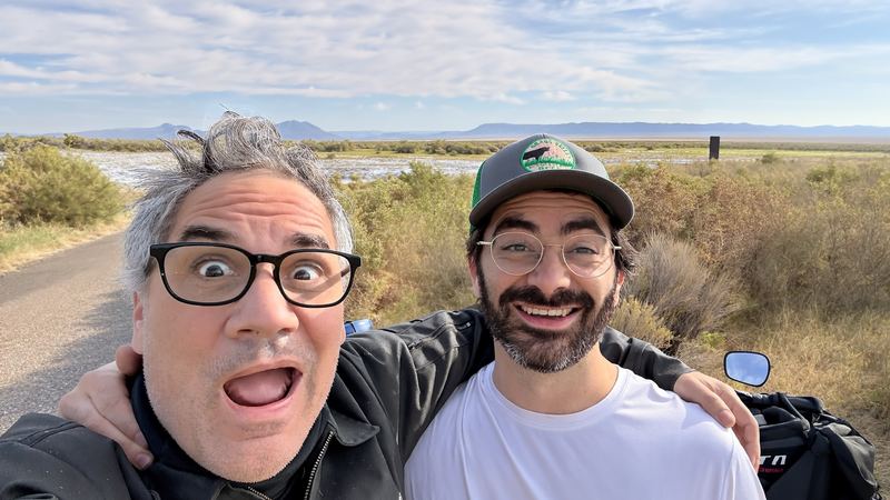 Two riders taking a goofy selfie on a desert road