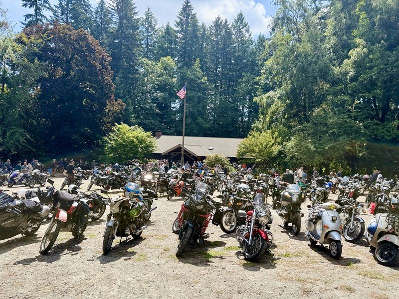 Rows of parked motorcycles in front of a lodge with an American flag